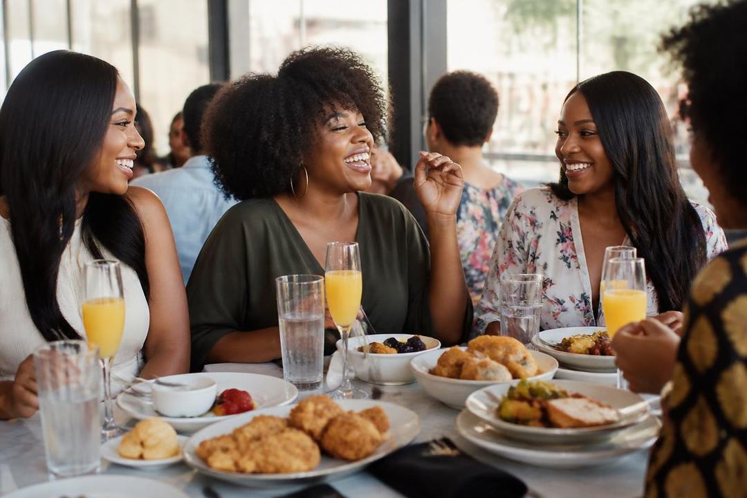 Friends laughing over brunch plates and mimosas at a bright restaurant